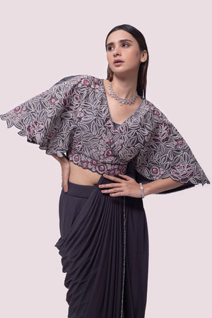 Shop grey net pre-stitched saree with flared blouse. Make a fashion statement on festive occasions and weddings with designer sarees, designer suits, Indian dresses, Anarkali suits, palazzo suits, designer gowns, sharara suits, and embroidered sarees from Pure Elegance Indian fashion store in the USA.