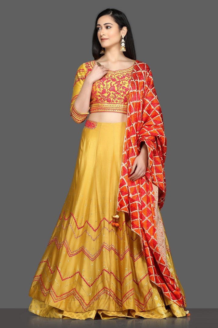 Buy gorgeous yellow embroidered lehenga online in USA with red and orange dupatta. Dazzle on weddings and special occasions with exquisite Indian designer dresses, sharara suits, Anarkali suits, bridal lehegas from Pure Elegance Indian fashion store in USA.-full view