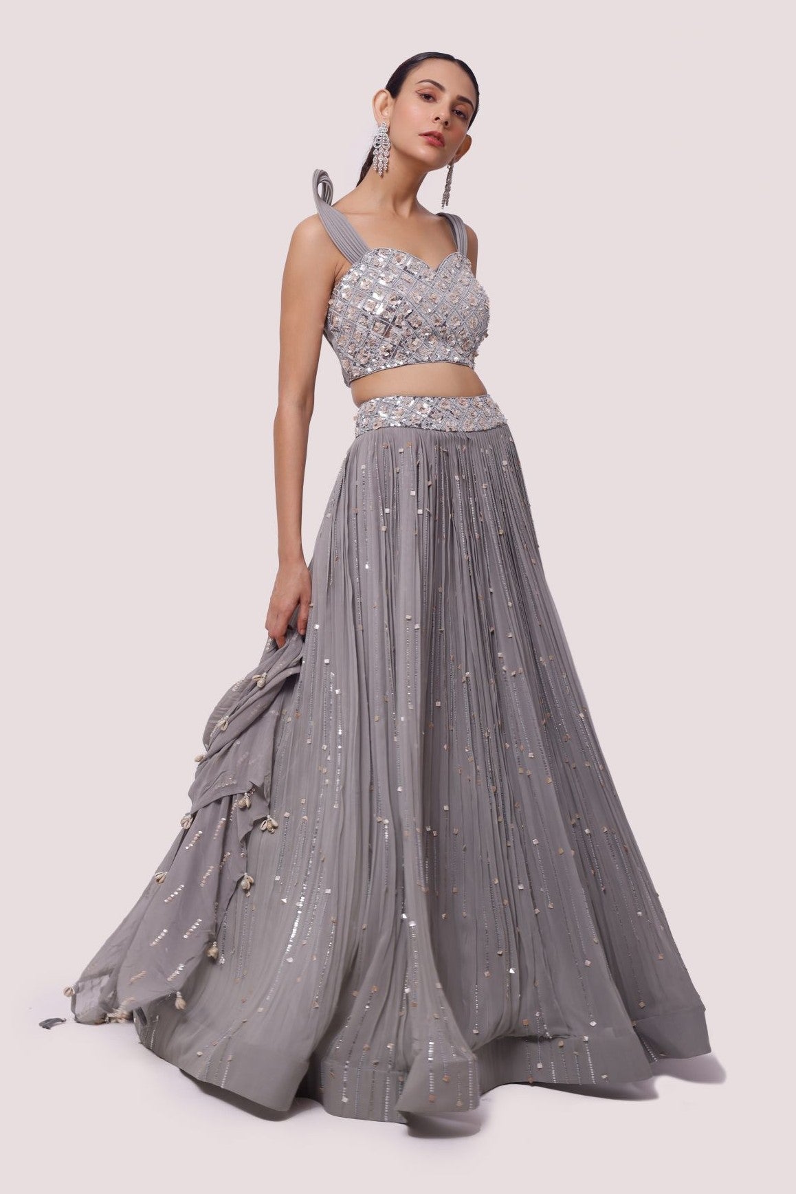 Buy a beautiful grey strappy sleeves lehenga featuring mirror work. The lehenga is perfect for weddings, and sangeet parties. Shop online from Pure Elegance.