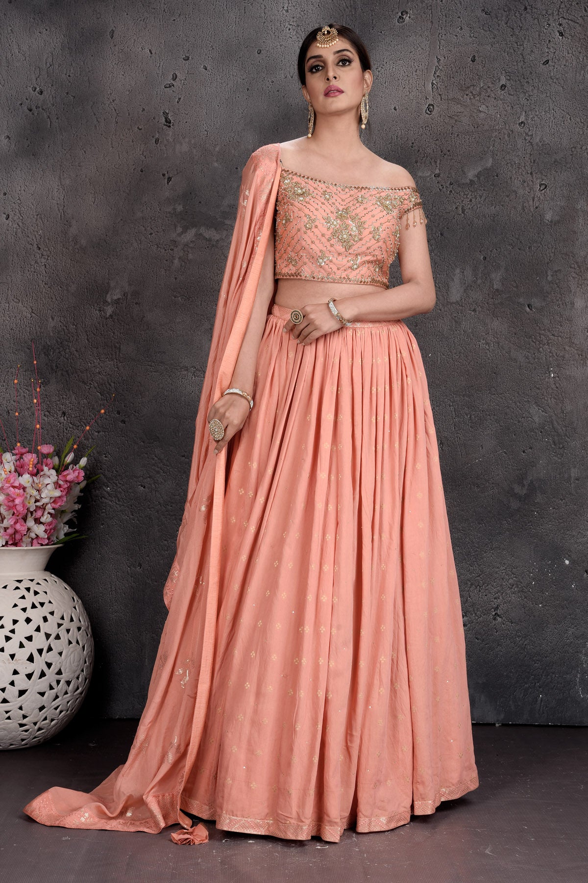 Shop beautiful peach off-shoulder designer lehenga online in USA with attached dupatta. Set a fashion statement at parties in designer Indian suits, Anarkali suits, designer lehengas, gowns, Indowestern dresses from Pure Elegance Indian fashion store in USA.-front