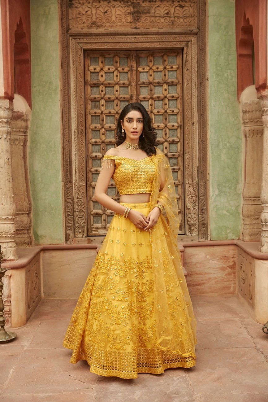 Buy stunning yellow thread embroidery off-shoulder net lehenga online in USA with dupatta. Elevate your ethnic style with a tasteful collection of designer Anarkali, designer salwar suits, designer lehengas, sharara suits from Pure Elegance Indian clothing store in USA.-full view