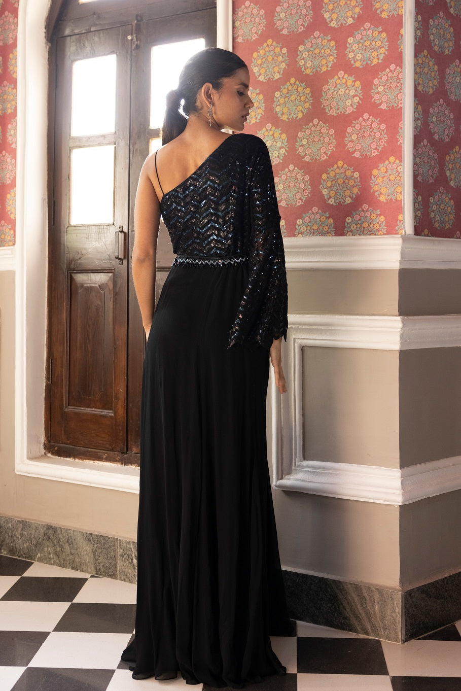 Beautiful black sequinned embroidered one-sided full sleeves and other side strappy sleeves gown. This gown is perfect for cocktail parties. Dazzle on weddings and special occasions with exquisite Indian designer dresses, sharara suits, Anarkali suits, and wedding lehengas from Pure Elegance Indian fashion store in the USA.