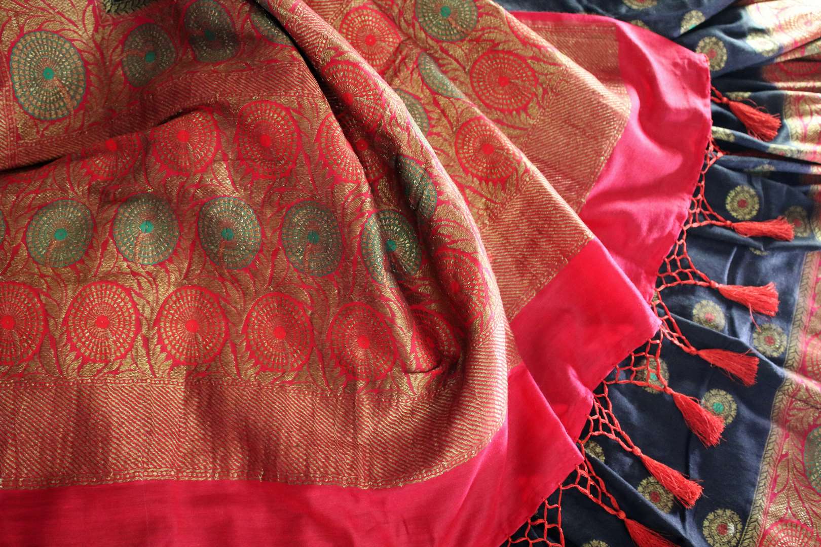 This black buta work muga banarsi silk sari complemented with a stunning red zari border and a heavily embroidered woven red pallu adds a touch of grace. Style it with a red designer blouse to strut at weddings or parties. Shop designer silk sarees, printed saris online or visit Pure Elegance store, USA. -details
