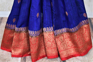 Shop indigo blue tussar Banarasi saree online in USA with zari buta and red antique zari border. Choose tasteful handloom saris for special occasions from Pure Elegance. Our exclusive Indian fashion store has a myriad of exquisite pure silk saris, tussar sarees, Banarasi sarees for Indian women in USA.-pleats