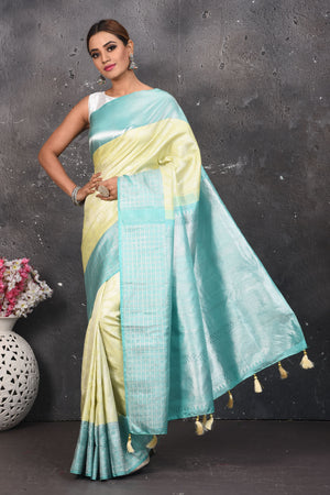 Shop this royal handwoven pure kanchiresham saree in pastel yellow with a firozi blue pallu online in USA. Presenting Enchanting Yet Breathable Organic Banarasi Saree Made from Kanjivaram silk. Drape yourself in this beautiful banarasi saree from Pure Elegance Indian Fashion Store in USA with Zari woven Border with a potli bag and high heels for a flawless look.- Full view.