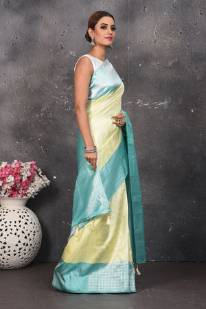 Shop this royal handwoven pure kanchiresham saree in pastel yellow with a firozi blue pallu online in USA. Presenting Enchanting Yet Breathable Organic Banarasi Saree Made from Kanjivaram silk. Drape yourself in this beautiful banarasi saree from Pure Elegance Indian Fashion Store in USA with Zari woven Border with a potli bag and high heels for a flawless look.- Side view.