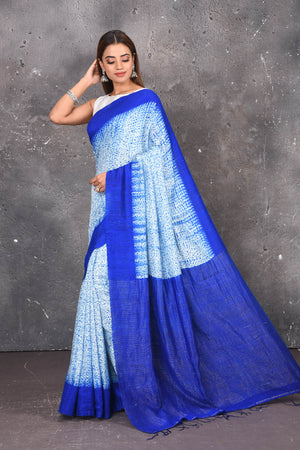 Shop this elegant offwhite-blue handloom shibori tussar saree online in USA which is handcrafted from fine silk tussar fabric, this tie and dye saree brings out the nature of flow. You can pair this beautiful shibori print with minimal jewellery for a casual day outfit. Add this plain shibori saree to your collection from Pure Elegance Indian fashion store in USA.-Side view.