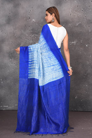 Shop this elegant offwhite-blue handloom shibori tussar saree online in USA which is handcrafted from fine silk tussar fabric, this tie and dye saree brings out the nature of flow. You can pair this beautiful shibori print with minimal jewellery for a casual day outfit. Add this plain shibori saree to your collection from Pure Elegance Indian fashion store in USA.-Back view with open pallu.