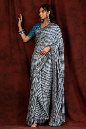 Shop blue stripes crepe saree online in USA with scalloped border. Make a fashion statement at weddings with stunning designer sarees, embroidered sarees with blouse, wedding sarees, handloom sarees from Pure Elegance Indian fashion store in USA.-front