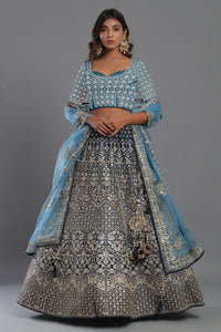 Shop a beautiful blue silk lehenga with a multicolor dupatta. The lehenga is perfect for weddings and sangeet parties. It is crafted in silk with intrinsic floral self-design work, tassels, and a beautiful off-white blouse. Shop online from Pure Elegance.