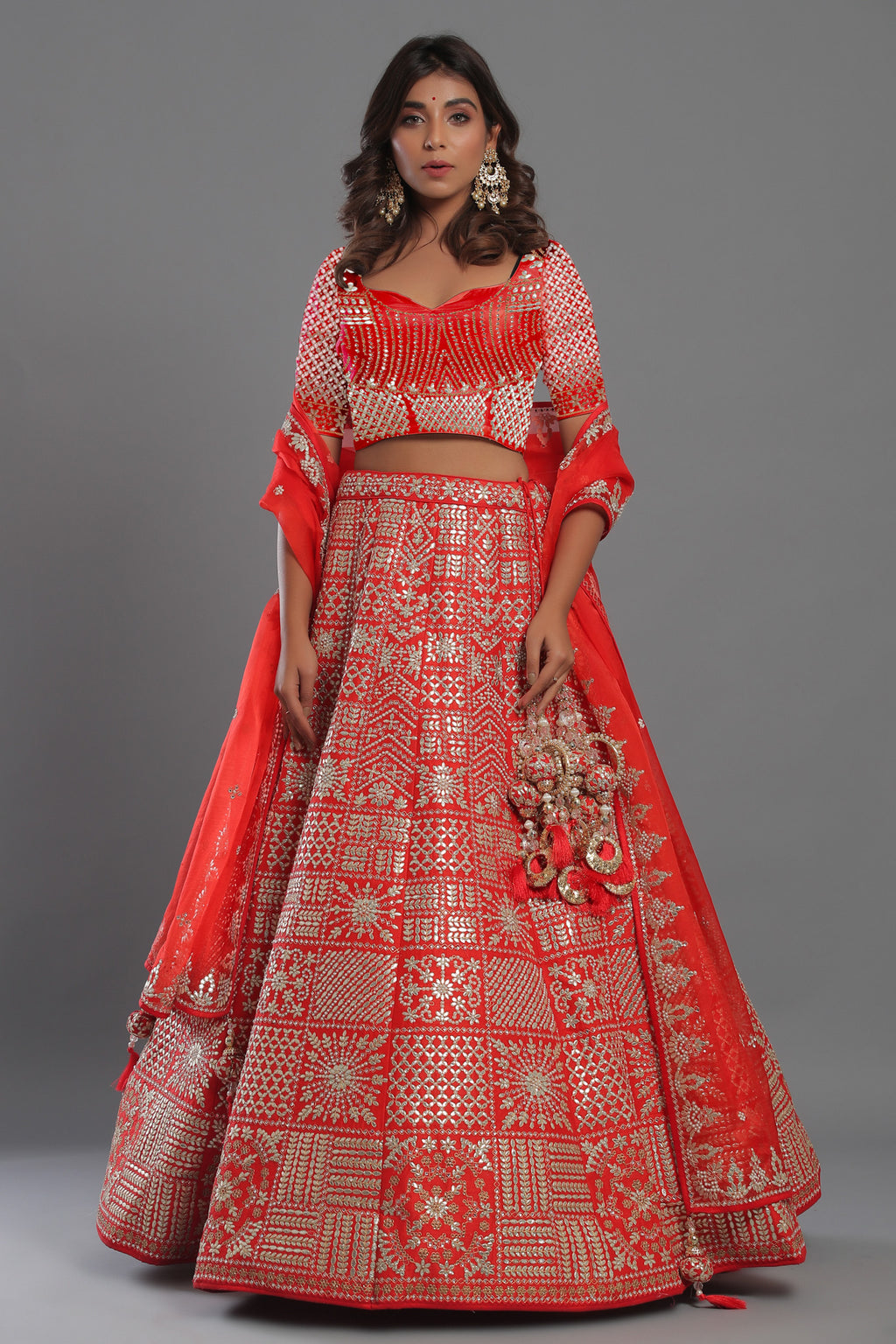 Shop red heavily silver embroidered lehenga with red net dupatta. The lehenga is perfect for a wedding party. It is crafted in silk with intrinsic zari embroidery on lehenga and blouse all over, tassels on a dupatta, with beautiful heavy tassles attached on the lehenga . Shop online from Pure Elegance.