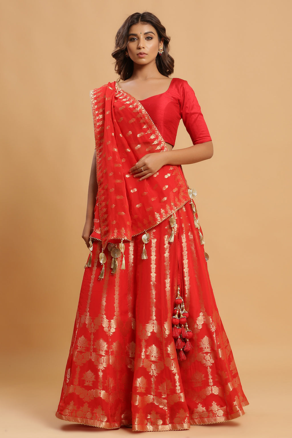 Shop orange zari embroidered lehenga with attached dupatta. It is crafted in silk with intrinsic zari embroidery on the lehenga and solid blouse tassels on a dupatta, with beautiful heavy tassels attached to the lehenga. Shop online from Pure Elegance.
