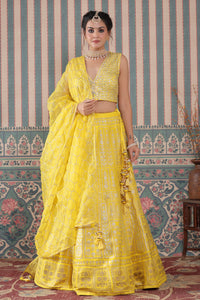 Shop a yellow lehenga set featuring a heavy Zari Embroidered Silk Lehenga Set. It comes with a beautiful V-neck blouse and zip closure. It has tassels attached to the lehenga. Pair it with beautiful jewelry to enhance your look. Shop online from Pure Elegance.