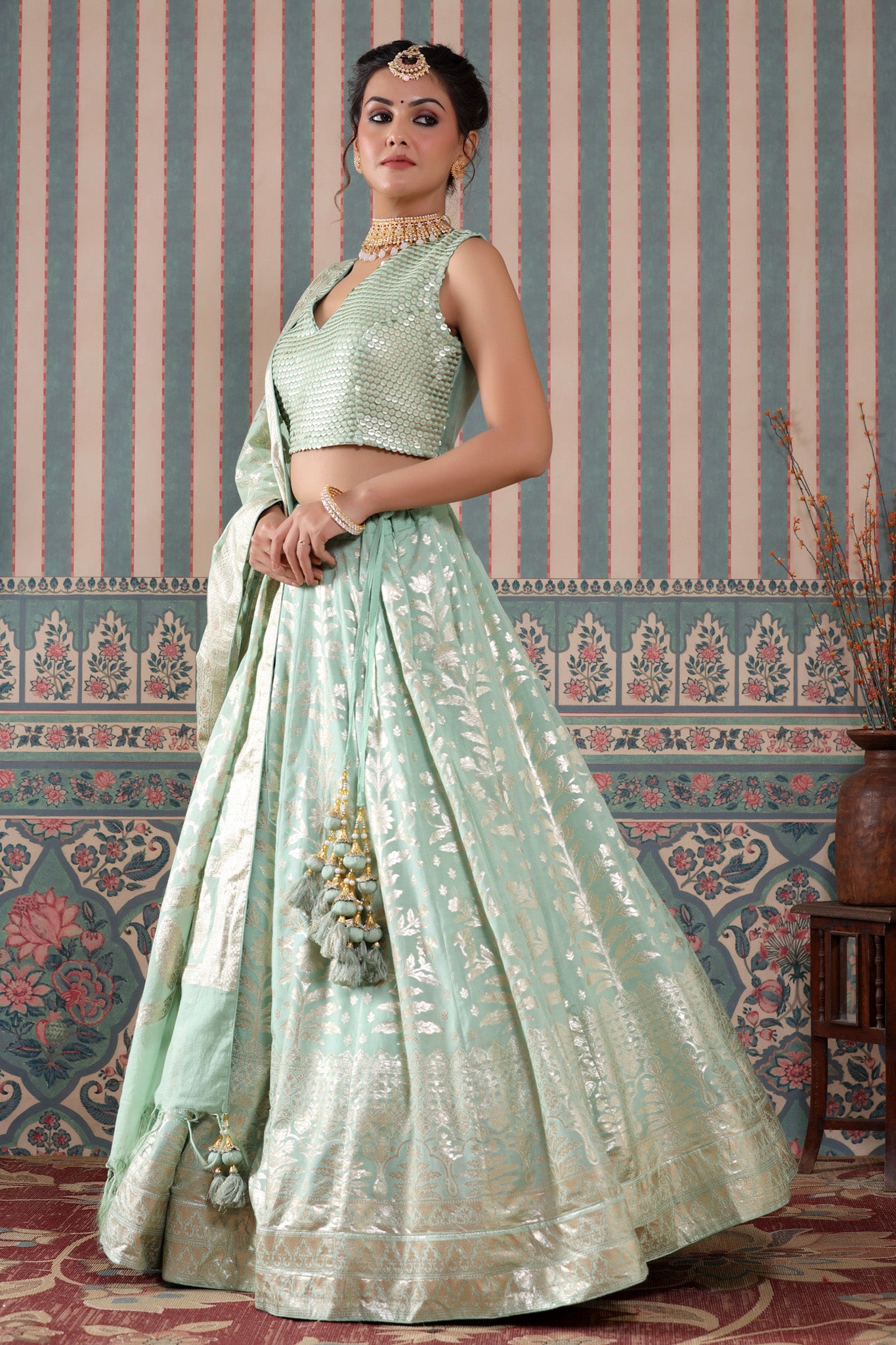 Shop a turquoise lehenga set featuring a floral zari embroidered silk lehenga set. It comes with a beautiful V-neck blouse and zip closure. It has tassels attached to the lehenga. Pair it with beautiful jewelry to enhance your look. Shop online from Pure Elegance.
