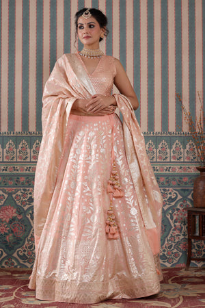 Shop a peach lehenga set featuring a floral zari embroidered silk lehenga set. It comes with a beautiful V-neck blouse and zip closure. It has tassels attached to the lehenga. Pair it with beautiful jewelry to enhance your look. Shop online from Pure Elegance.
