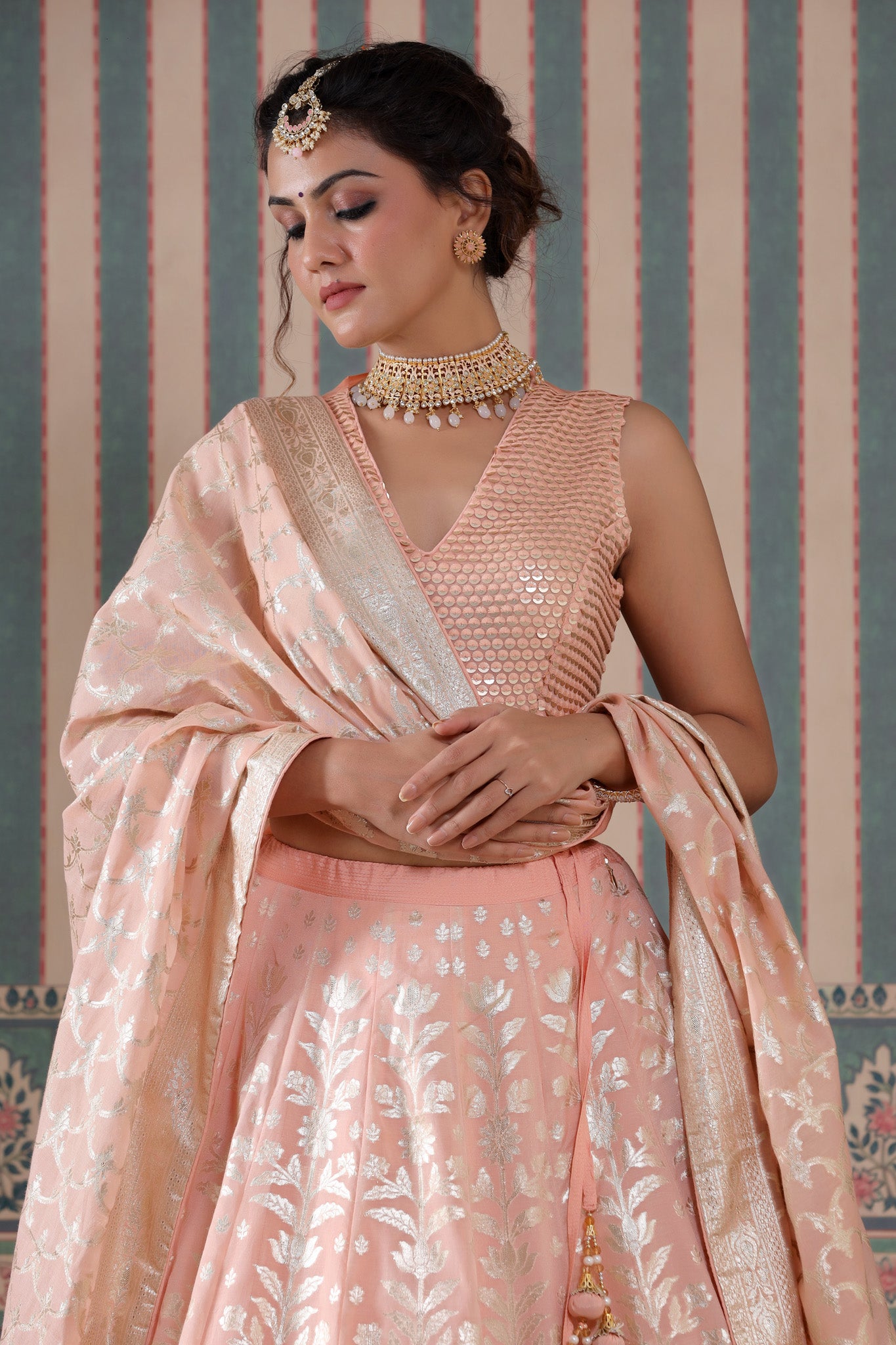 Shop a peach lehenga set featuring a floral zari embroidered silk lehenga set. It comes with a beautiful V-neck blouse and zip closure. It has tassels attached to the lehenga. Pair it with beautiful jewelry to enhance your look. Shop online from Pure Elegance.