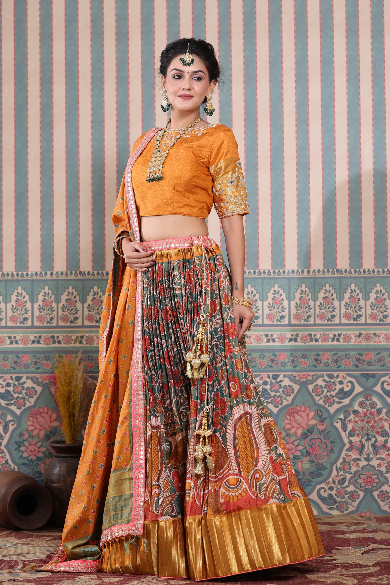 Shop a mustard floral printed lehenga set featuring gota patti work and a silk dupatta set. It comes with a beautiful mustard blouse embroidered with gota patti work. Pair it with beautiful jewelry to enhance your look. Shop online from Pure Elegance.