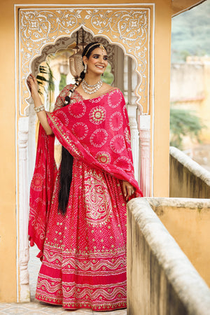 Shop a pink bandhej print beautiful lehenga set with gota patti work and long tassel attached on the lehenga. it comes with a pink blouse with heavy embroidery, hook closure, and tie-up at the back. Pair it with beautiful Rajasthani jewelry to enhance your look. Shop online from Pure Elegance.