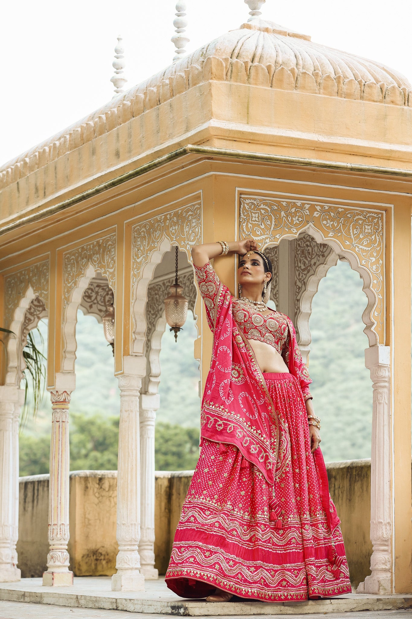 Shop a pink bandhej print beautiful lehenga set with gota patti work and long tassel attached on the lehenga. it comes with a pink blouse with heavy embroidery, hook closure, and tie-up at the back. Pair it with beautiful Rajasthani jewelry to enhance your look. Shop online from Pure Elegance.
