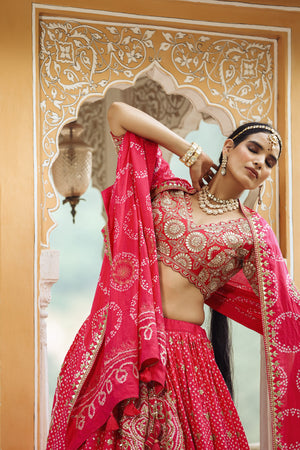 Shop a pink bandhej print beautiful lehenga set with gota patti work and long tassel attached on the lehenga. it comes with a pink blouse with heavy embroidery, hook closure, and tie-up at the back. Pair it with beautiful Rajasthani jewelry to enhance your look. Shop online from Pure Elegance.