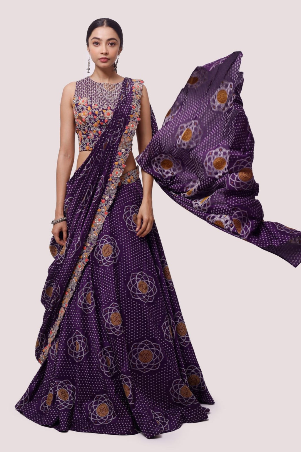 Shop purple lehenga and dupatta set with bandhani work and embroidered blouse. Dazzle on weddings and special occasions with exquisite Indian designer dresses, sharara suits, Anarkali suits, bridal lehengas, and sharara suits from Pure Elegance Indian clothing store in the USA. Shop online from Pure Elegance.