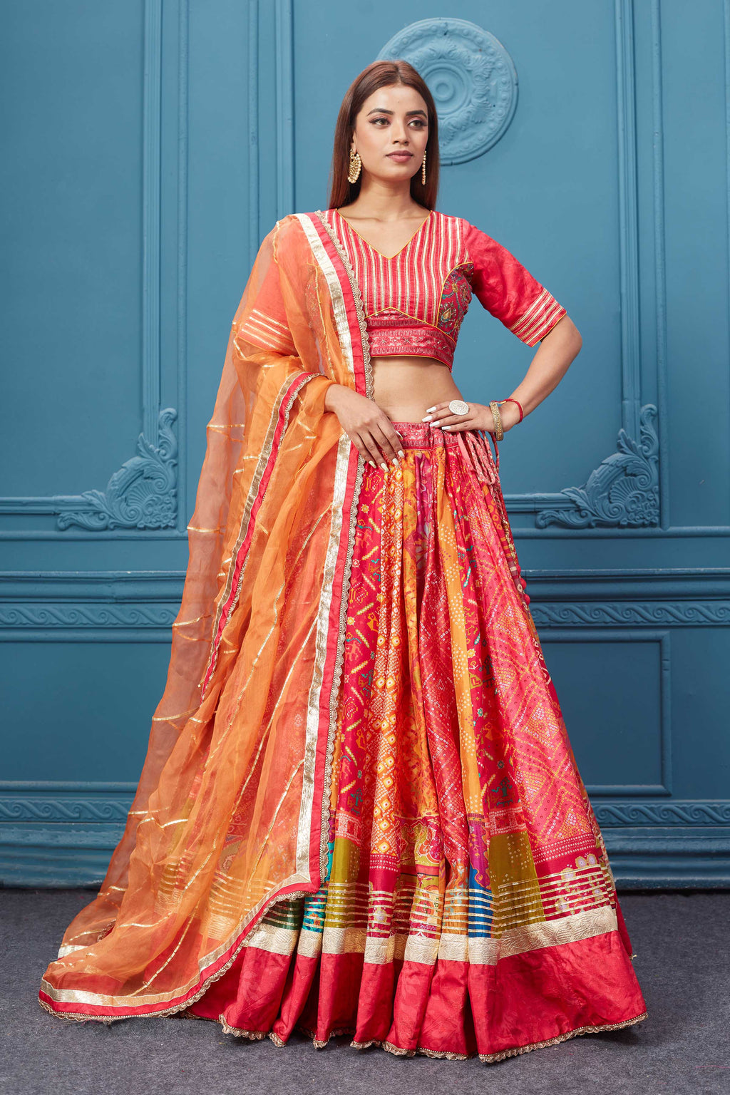 Buy this Red embroidered bandhej lehenga with a contrasting orange dupatta online in the USA. Featuring embroidered blouse with 3/4th sleeves blouse The Lehenga comes with a look royal at weddings and festive occasions in exquisite designer sarees, gowns, lehngas, Anarkali, and suits Pure Elegance Indian saree stores in the USA.