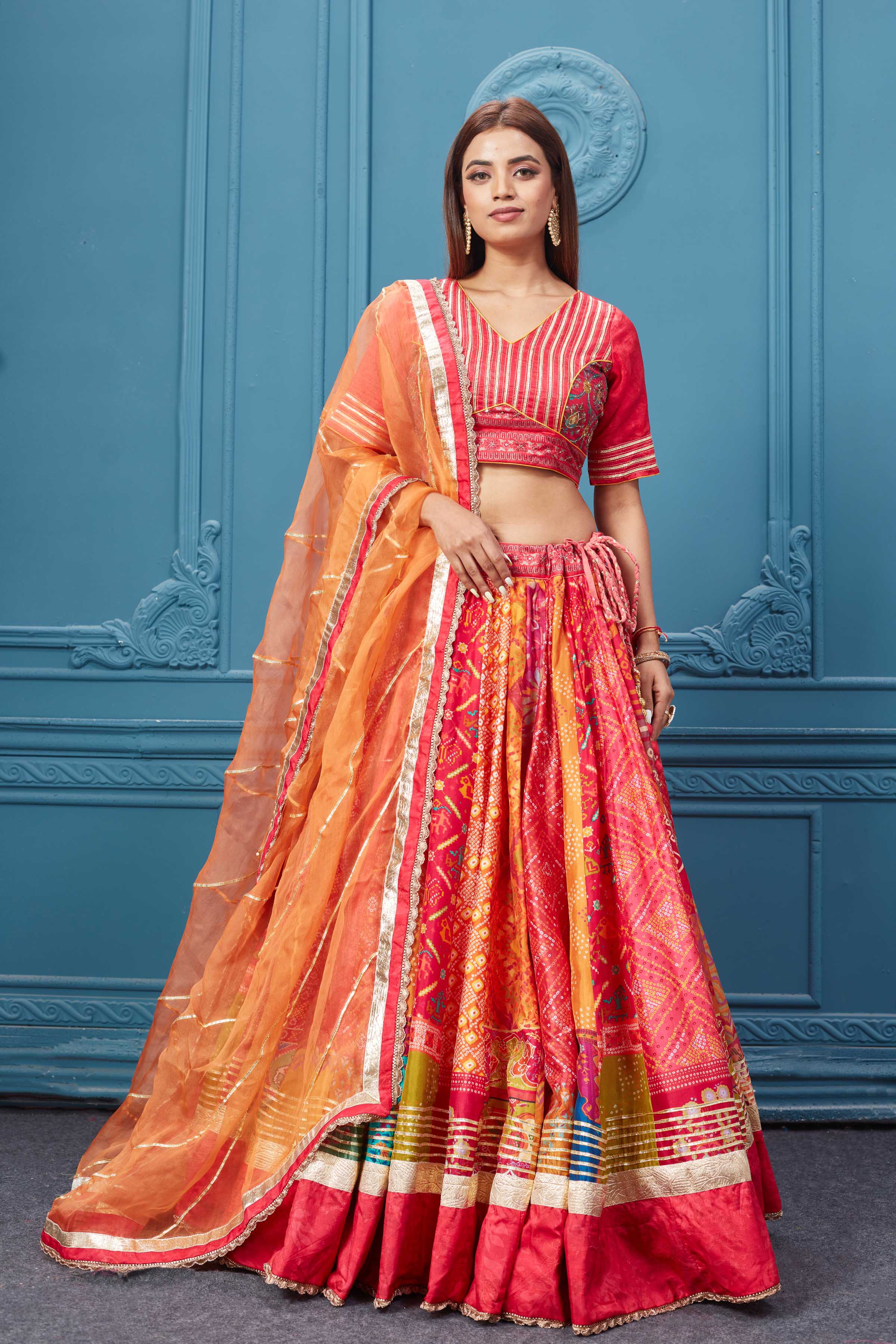 Buy this Red embroidered bandhej lehenga with a contrasting orange dupatta online in the USA. Featuring embroidered blouse with 3/4th sleeves blouse The Lehenga comes with a look royal at weddings and festive occasions in exquisite designer sarees, gowns, lehngas, Anarkali, and suits Pure Elegance Indian saree stores in the USA.