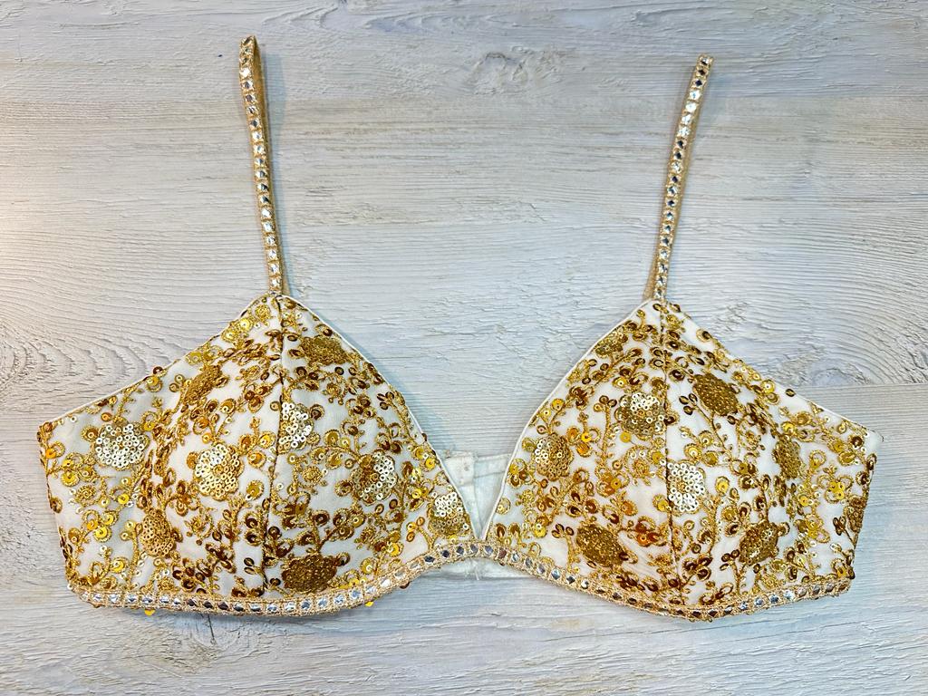 Buy white strappy blouse with golden floral sequin embroidery. Make a fashion statement on festive occasions and weddings with designer blouses, designer sarees, designer suits, Indian dresses, designer gowns, sharara suits, and embroidered sarees from Pure Elegance Indian fashion store in the USA.