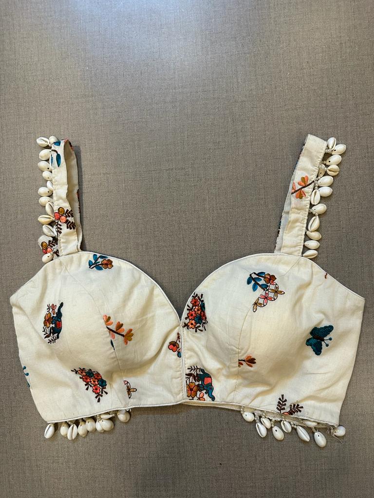 Buy white strappy blouse with embroidery work & hanging shells. Make a fashion statement on festive occasions and weddings with designer blouses, designer sarees, designer suits, Indian dresses, designer gowns, sharara suits, and embroidered sarees from Pure Elegance Indian fashion store in the USA.