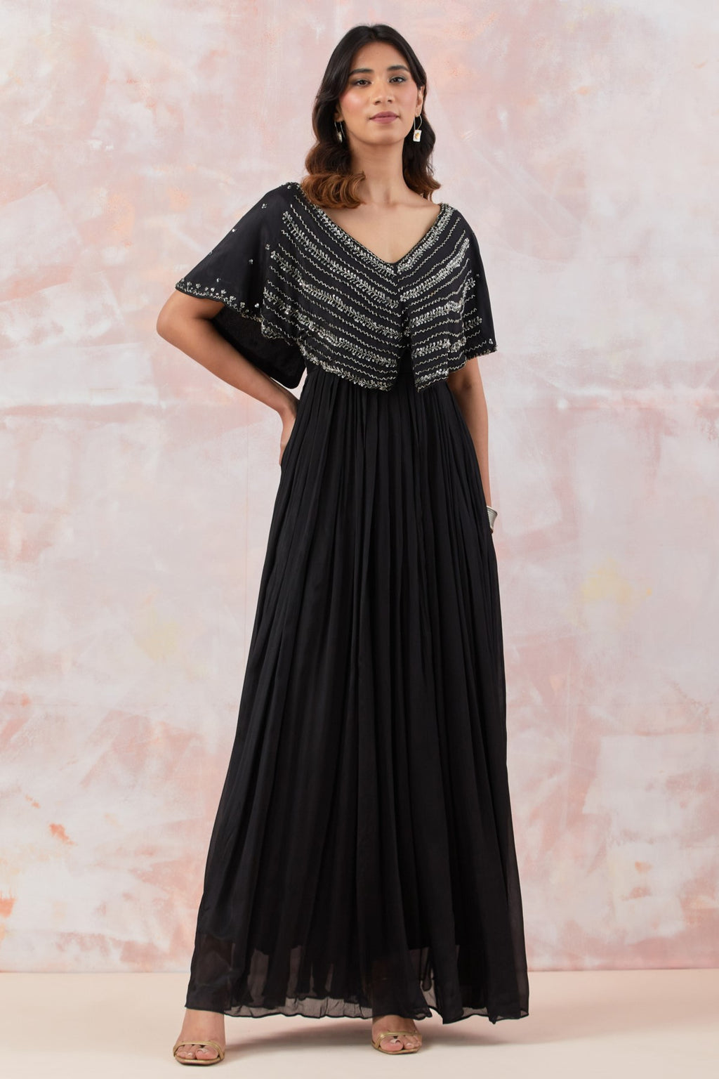 Buy Black caped gown featuring intricate handwork and immaculate detailing. It is best suited for occasions & parties. Dazzle on weddings and special occasions with exquisite Indian designer dresses, sharara suits, Anarkali suits, and wedding lehengas from Pure Elegance Indian fashion store in the USA.