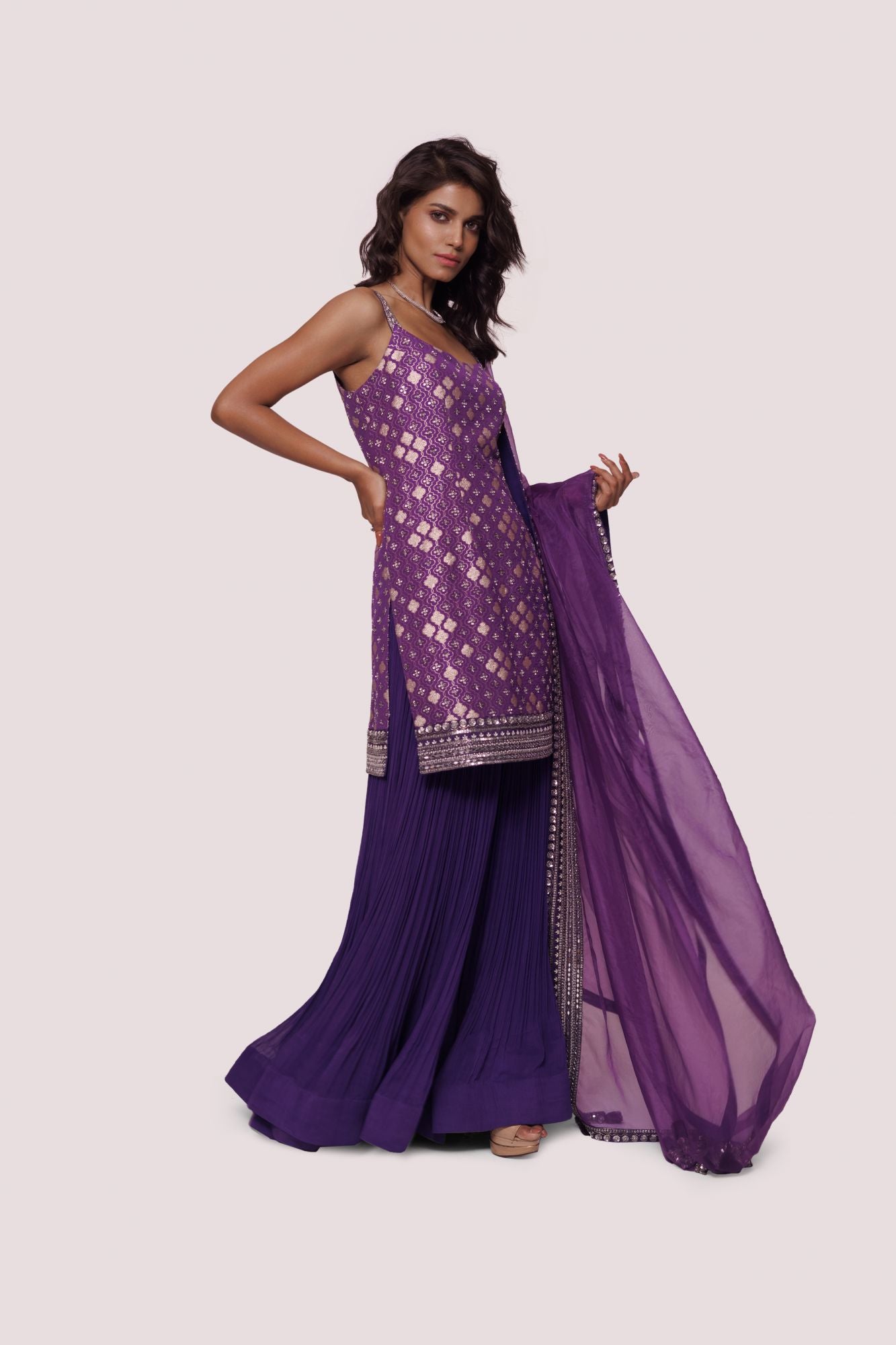 Buy a purple brocade kurta set with georgette sharara and narrow sleeves with sequin mirror embroidery. Dazzle on weddings and special occasions with exquisite Indian designer dresses, sharara suits, Anarkali suits, and wedding lehengas from Pure Elegance Indian fashion store in the USA.