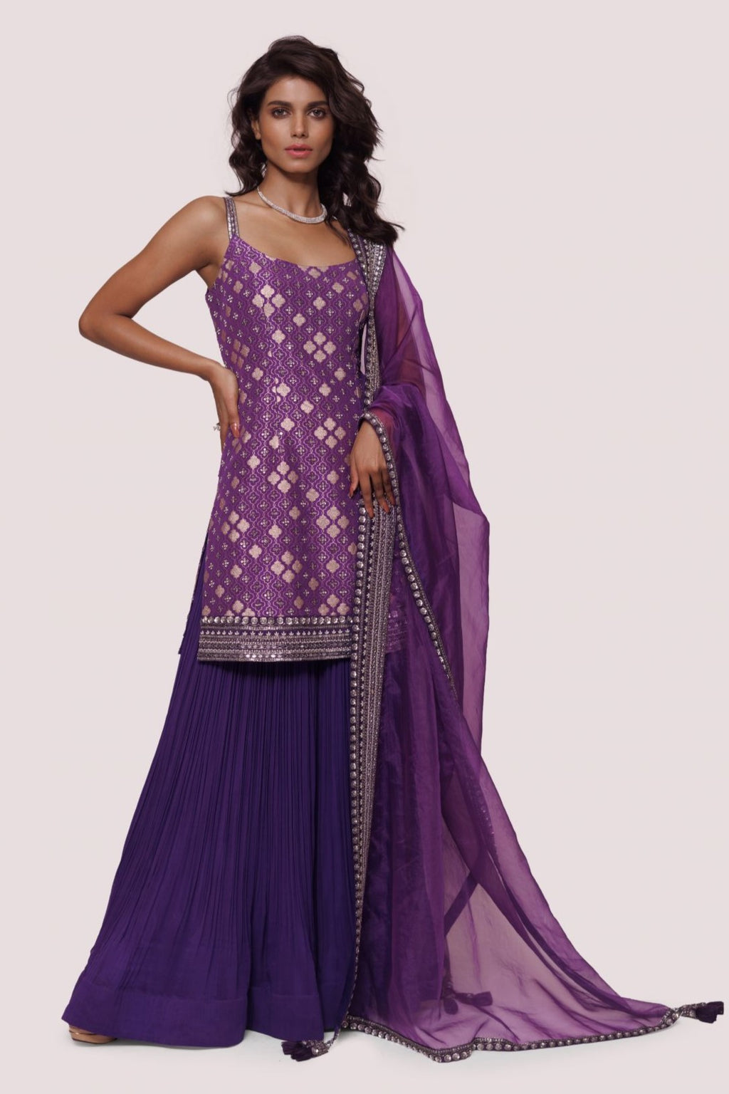 Buy a purple brocade kurta set with georgette sharara and narrow sleeves with sequin mirror embroidery. Dazzle on weddings and special occasions with exquisite Indian designer dresses, sharara suits, Anarkali suits, and wedding lehengas from Pure Elegance Indian fashion store in the USA.