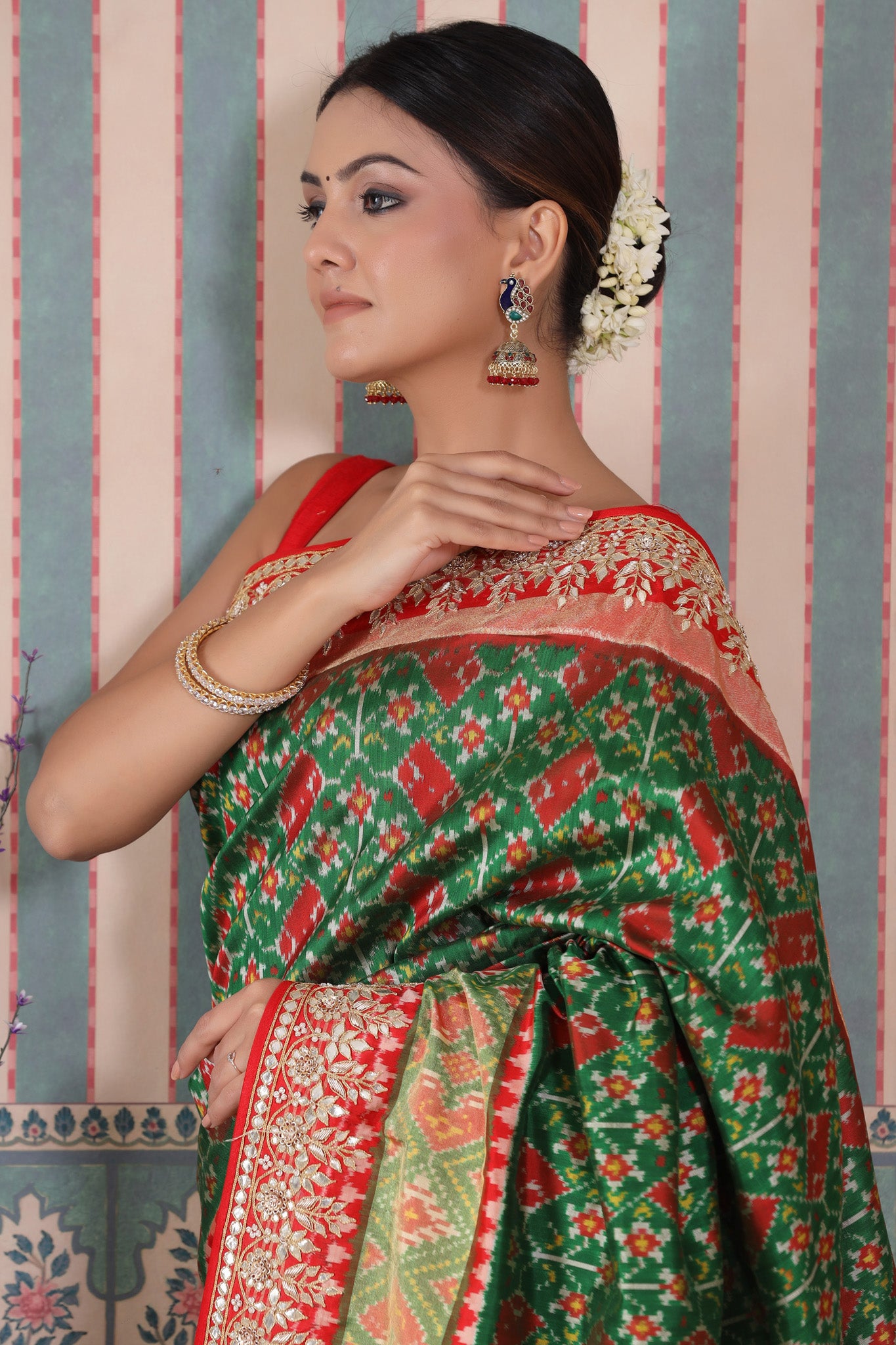 Shop green Patola silk sari online in USA with red embroidered border. Make a fashion statement at weddings with stunning designer sarees, embroidered sarees with blouse, wedding sarees, handloom sarees from Pure Elegance Indian fashion store in USA.-closeup
