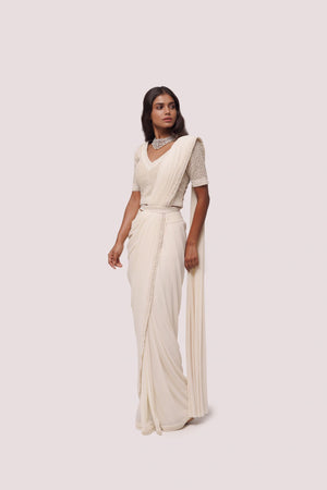 Shop off white drape saree with silver moti work. Make a fashion statement on festive occasions and weddings with designer sarees, designer suits, Indian dresses, Anarkali suits, palazzo suits, designer gowns, sharara suits, and embroidered sarees from Pure Elegance Indian fashion store in the USA.