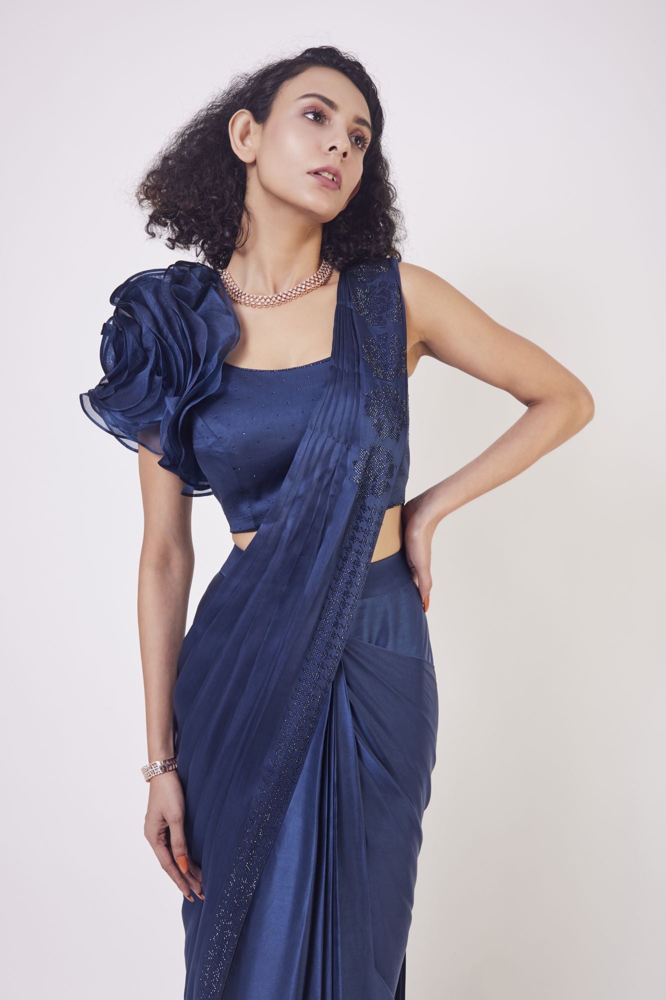 Shop navy blue satin drape dress with a designer blouse and floral design on the shoulder of the blouse. Make a fashion statement on festive occasions and weddings with designer sarees, designer suits, Indian dresses, Anarkali suits, palazzo suits, designer gowns, sharara suits, and embroidered sarees from Pure Elegance Indian fashion store in the USA.