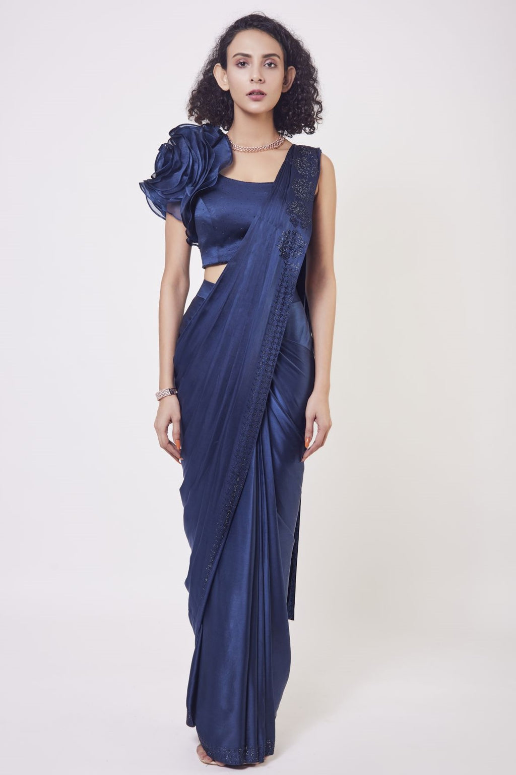 Shop navy blue satin drape dress with a designer blouse and floral design on the shoulder of the blouse. Make a fashion statement on festive occasions and weddings with designer sarees, designer suits, Indian dresses, Anarkali suits, palazzo suits, designer gowns, sharara suits, and embroidered sarees from Pure Elegance Indian fashion store in the USA.
