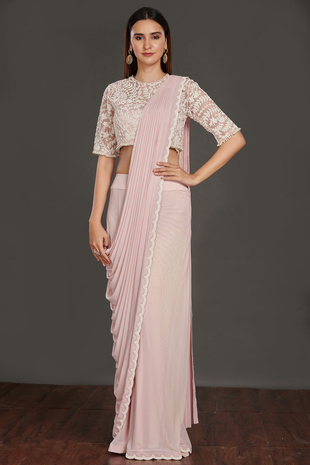 Shop pink satin drape with a designer white laced blouse. Make a fashion statement on festive occasions and weddings with designer sarees, designer suits, Indian dresses, Anarkali suits, palazzo suits, designer gowns, sharara suits, and embroidered sarees from Pure Elegance Indian fashion store in the USA.