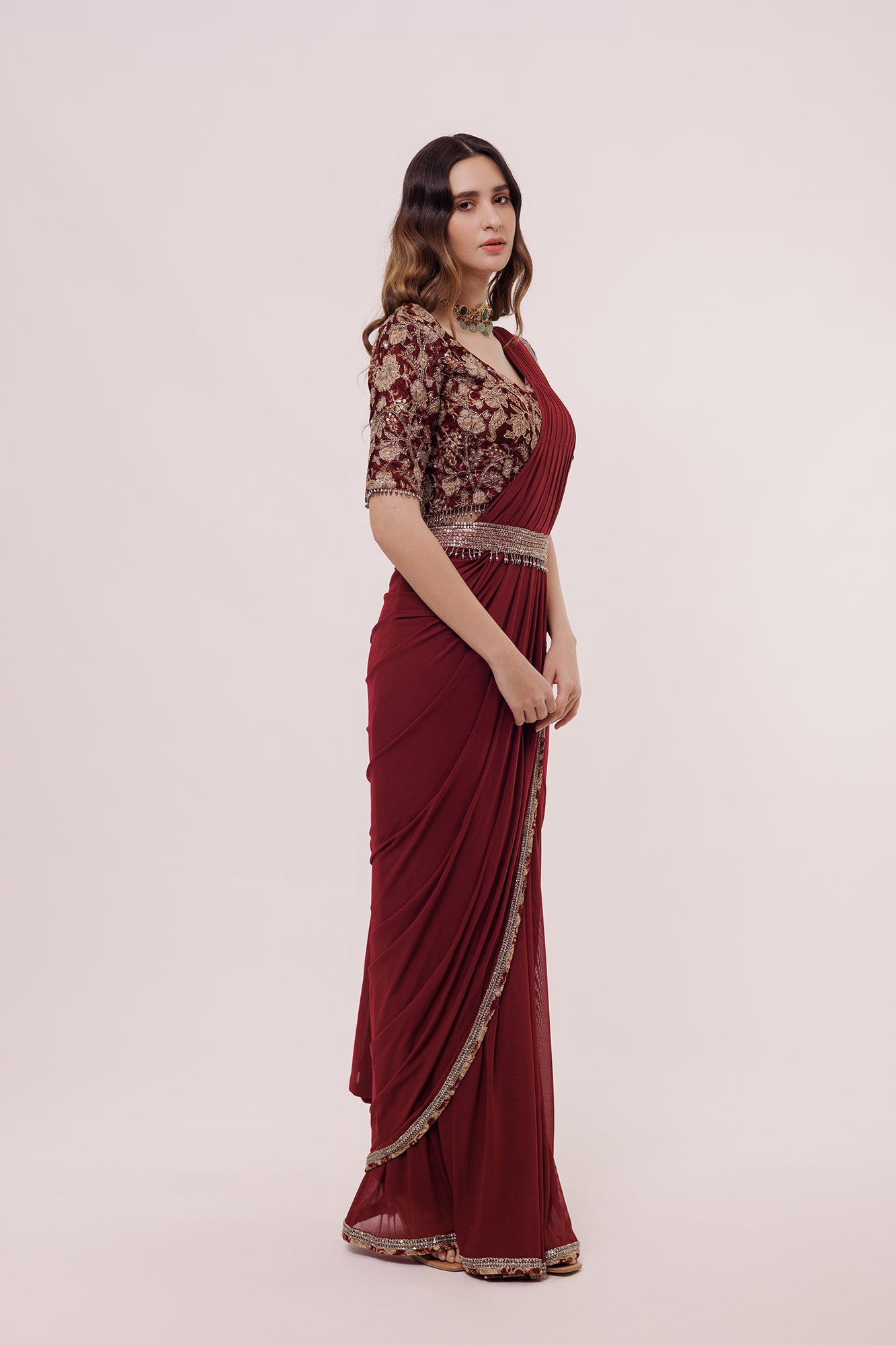 Shop wine net saree with embroidered edges and a narrow belt. Make a fashion statement on festive occasions and weddings with designer sarees, designer suits, Indian dresses, Anarkali suits, palazzo suits, designer gowns, sharara suits, and embroidered sarees from Pure Elegance Indian fashion store in the USA.