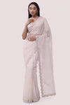 Shop a Beautiful off-white organza saree featuring threadwork and sparse embellishments. It comes with an embroidered blouse. Make a fashion statement on festive occasions and weddings with designer sarees, designer suits, Indian dresses, Anarkali suits, palazzo suits, designer gowns, sharara suits, and embroidered sarees from Pure Elegance Indian fashion store in the USA.