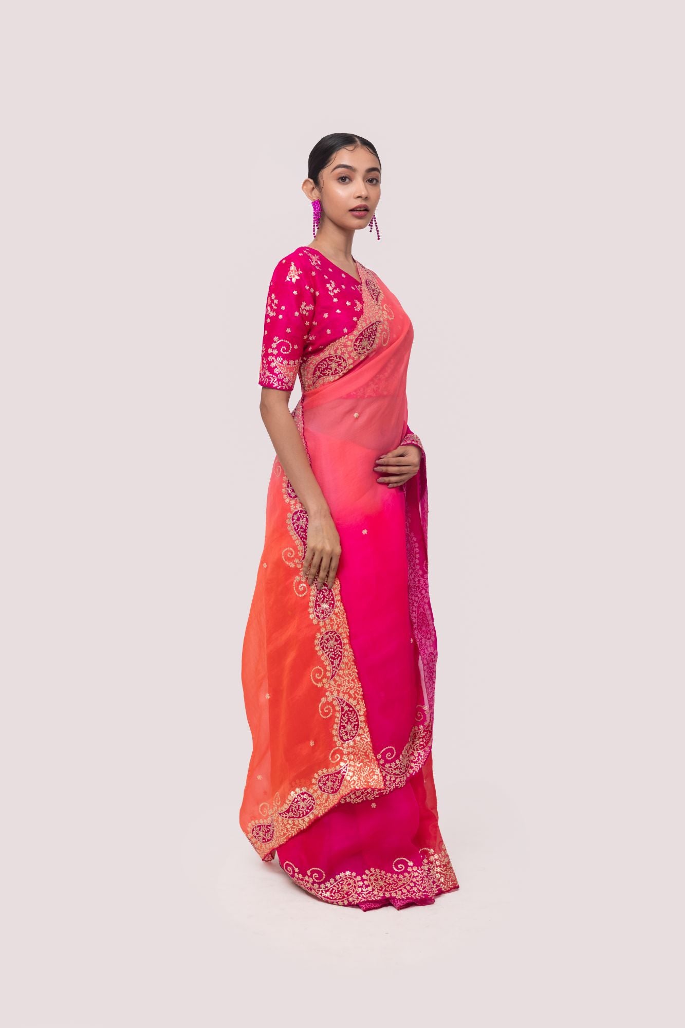 Shop a pink organza saree featuring zari embroidered edges. Make a fashion statement on festive occasions and weddings with designer sarees, designer suits, Indian dresses, Anarkali suits, palazzo suits, designer gowns, sharara suits, and embroidered sarees from Pure Elegance Indian fashion store in the USA.