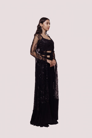 Shop black sequinned saree with cape jacket blouse. Make a fashion statement on festive occasions and weddings with designer sarees, designer suits, Indian dresses, Anarkali suits, palazzo suits, designer gowns, sharara suits, and embroidered sarees from Pure Elegance Indian fashion store in the USA.