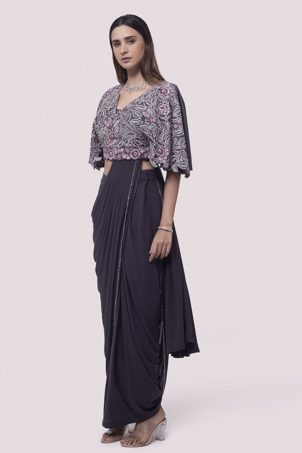 Shop grey net pre-stitched saree with flared blouse. Make a fashion statement on festive occasions and weddings with designer sarees, designer suits, Indian dresses, Anarkali suits, palazzo suits, designer gowns, sharara suits, and embroidered sarees from Pure Elegance Indian fashion store in the USA.