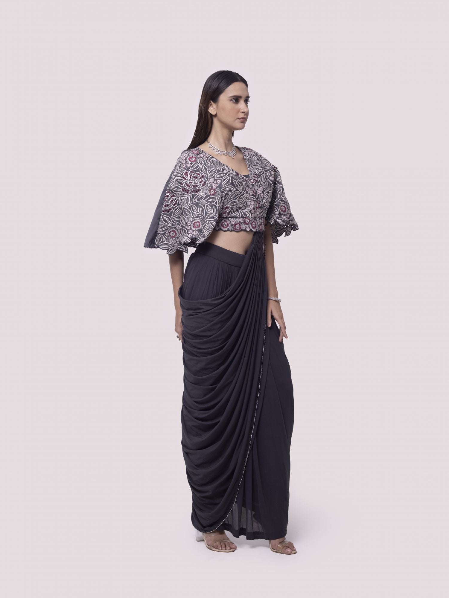 Shop grey net pre-stitched saree with flared blouse. Make a fashion statement on festive occasions and weddings with designer sarees, designer suits, Indian dresses, Anarkali suits, palazzo suits, designer gowns, sharara suits, and embroidered sarees from Pure Elegance Indian fashion store in the USA.