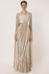 Shop a beige drape saree with statement cape sleeves. Make a fashion statement on festive occasions and weddings with designer sarees, designer suits, Indian dresses, Anarkali suits, palazzo suits, designer gowns, sharara suits, and embroidered sarees from Pure Elegance Indian fashion store in the USA.