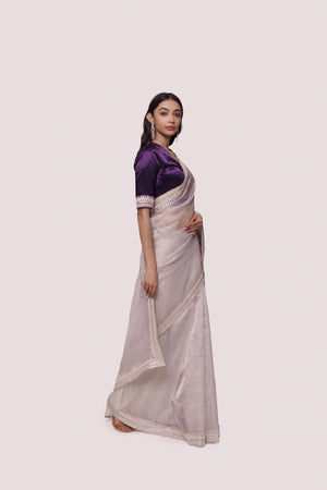 Shop grey saree with Indian embroidered contrasting purple blouse. Make a fashion statement on festive occasions and weddings with designer sarees, designer suits, Indian dresses, Anarkali suits, palazzo suits, designer gowns, sharara suits, and embroidered sarees from Pure Elegance Indian fashion store in the USA.