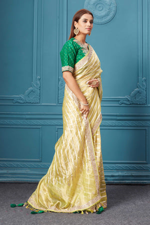Buy yellow tissue Kora silk saree online in USA with green saree blouse. Look royal at weddings and festive occasions in exquisite designer sarees, handwoven sarees, pure silk saris, Banarasi sarees, Kanchipuram silk sarees from Pure Elegance Indian saree store in USA. -side