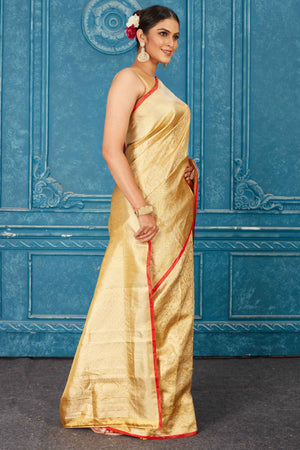 Buy beautiful golden Kanjeevaram silk sari online in USA with red edging. Radiate glam at parties in dazzling designer sarees, party sarees, embroidered sarees, sequin work sarees, Bollywood sarees, handloom sarees from Pure Elegance Indian saree store in USA.-side