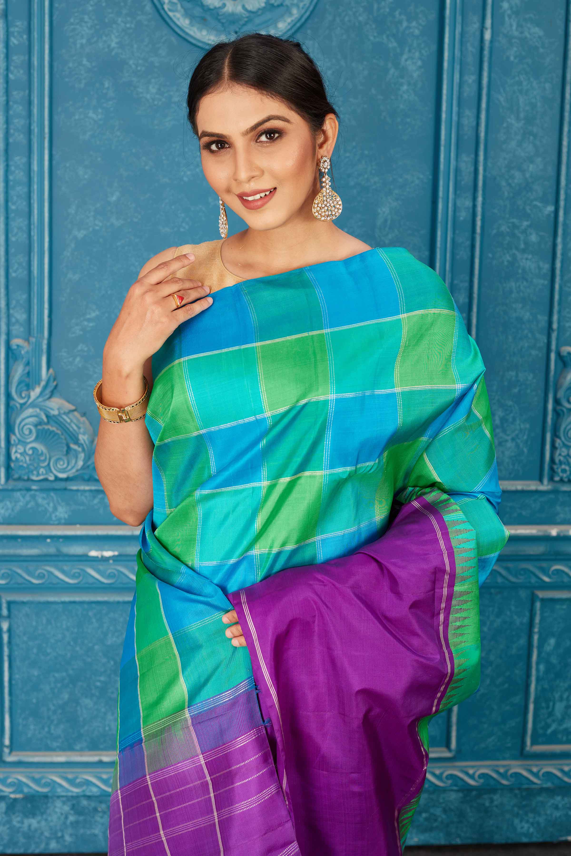 Shop beautiful green and blue check Kanjeevaram silk sari online in USA with purple border. Radiate glam at parties in dazzling designer sarees, party sarees, embroidered sarees, sequin work sarees, Bollywood sarees, handloom sarees from Pure Elegance Indian saree store in USA.-closeup