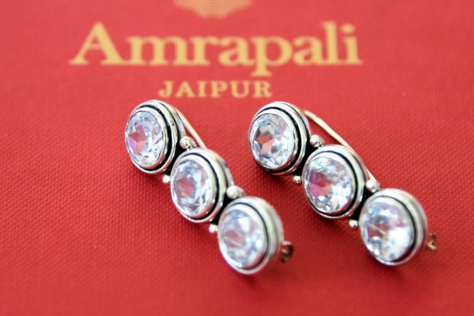 Shop beautiful Amrapali silver earrings online in USA with zircon stone. Complete your festive look with exclusive silver gold plated jewelry, gold plated earrings, silver jewelry, silver earrings from Pure Elegance Indian fashion store in USA.-flatlay