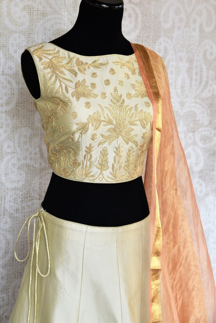 Buy beautiful cream embroidered silk lehenga choli set online in USA. The elegant attire is a perfect pick for an ethnic look at wedding and parties. Get floored by an exclusive collection of Indian designer lehengas in USA available at Pure Elegance fashion store or shop online.-side view